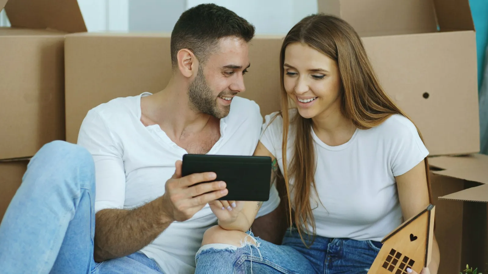 Couple d’acquéreurs consultant des annonces sur une tablette avant de contacter une agence