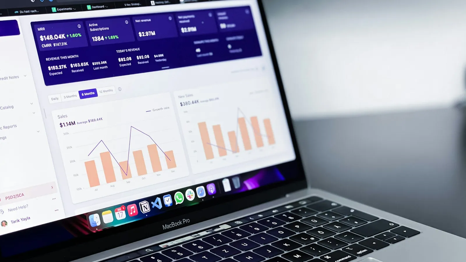 Laptop menampilkan dashboard aplikasi CRM properti dengan grafik penjualan